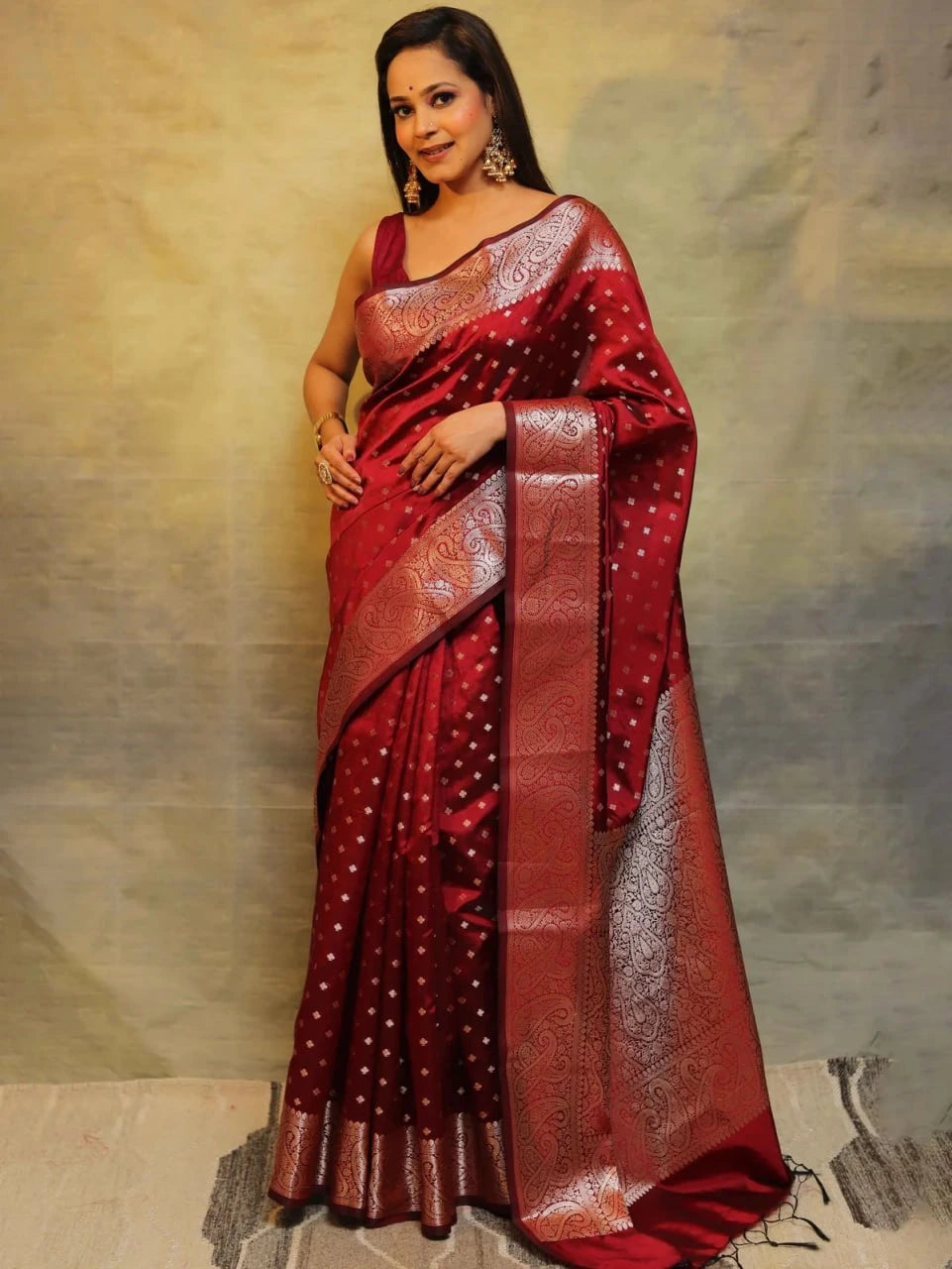 Woman wearing a red saree with white patterns against a neutral background